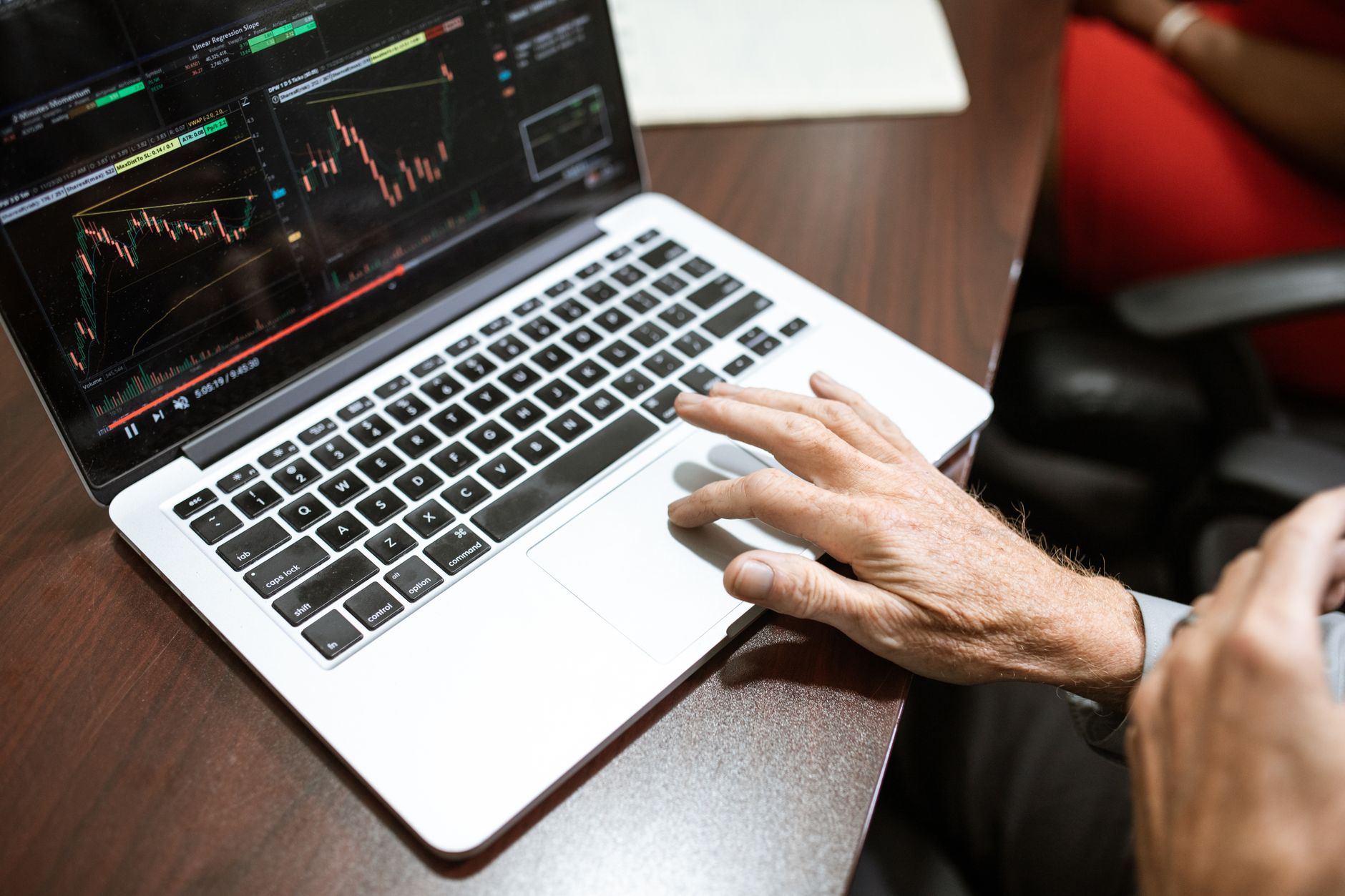 Trader concentrado analizando gráficos financieros y datos de mercado en múltiples pantallas, aplicando estrategias de gestión de riesgo.