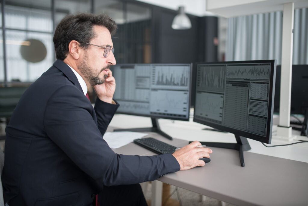 Empresario analizando datos macroeconómicos en una pantalla, tomando decisiones de inversión estratégicas.